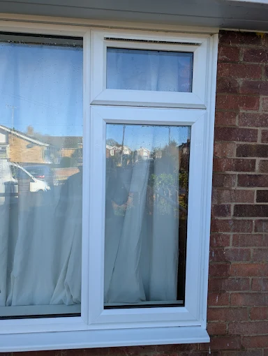 Professional window cleaning in Mildenhall showing a white window cleaned to a clear, reflective finish.